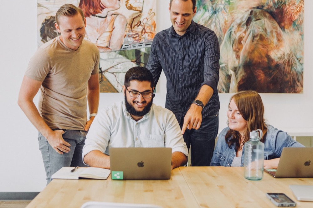 Small creative team reviewing work on a laptop